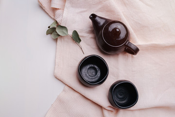 Black utensils, a teapot and two cups on a pink towel