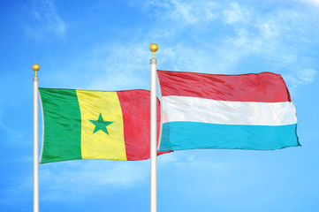 Senegal and Luxembourg two flags on flagpoles and blue cloudy sky