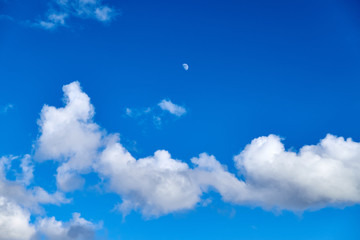 Blue sky background with white clouds and moon