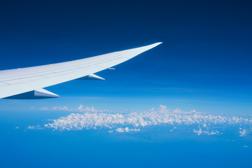 Airplane wing on blue sky with clouds background