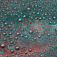 Turquoise and red spheres with green halo and their reflections are located on a motley background....