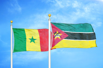 Senegal and Mozambique two flags on flagpoles and blue cloudy sky