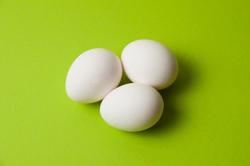 Several chicken eggs on bright green background, copy space