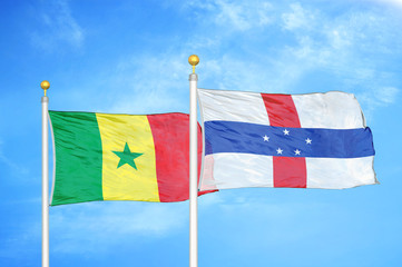 Senegal and Netherlands Antilles two flags on flagpoles and blue cloudy sky