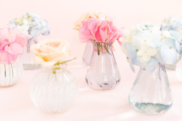 Decoration of blooming blue hydrangea, sweet pea Lathyrus, bush roses in small crystal vases on pink background. Design, Creative. International Women's Day,March 8 and Valentine's Day,14 of February