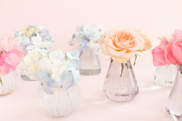 Decoration of blooming blue hydrangea, sweet pea Lathyrus, bush roses in small crystal vases on pink background. Design, Creative. International Women's Day,March 8 and Valentine's Day,14 of February
