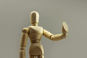 Wooden figure making stop sign on a gray background. Concept
