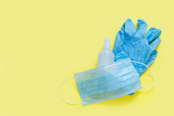 Antiseptic hand sanitizer, protection medical mask and latex gloves on yellow background. Concept of coronavirus protection, COVID-19 pandemic, global quarantine. Flat lay, top view. Copy space.