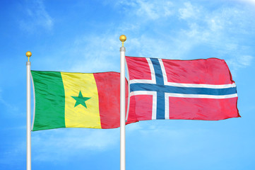 Senegal and Norway two flags on flagpoles and blue cloudy sky