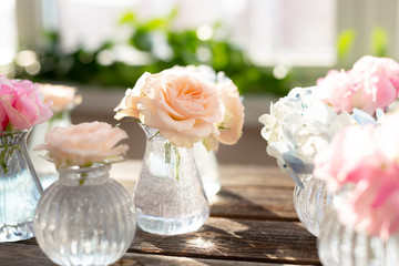 Decoration of blooming blue hydrangea, sweet pea Lathyrus, bush roses in small crystal vases on wooden background. Design,creative.International Women's Day,March 8 and Valentine's Day,14 of February