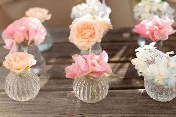 Decoration of blooming blue hydrangea, sweet pea Lathyrus, bush roses in small crystal vases on wooden background. Design,creative.International Women's Day,March 8 and Valentine's Day,14 of February