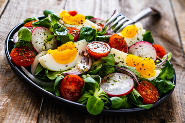 Salad with boiled egg and vegetables on wooden table
