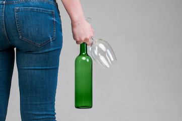 Bottle and a glass in the hands of a woman.