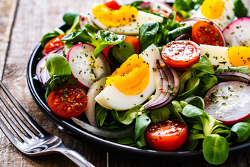 Salad with boiled egg and vegetables on wooden table
