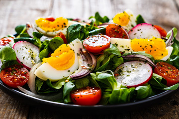 Salad with boiled egg and vegetables on wooden table
