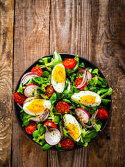 Salad with boiled egg and vegetables on wooden table
