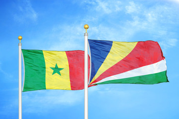 Senegal and Seychelles two flags on flagpoles and blue cloudy sky
