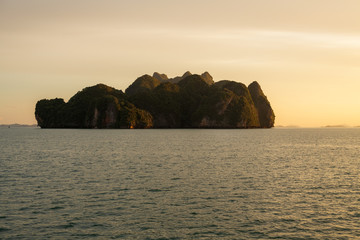 Beautiful golden sunset into the sea and beautiful limestone island of Phang-Nga bay near Phuket Thailand.