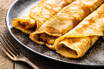Sweet crepes with fruit jam on wooden table
