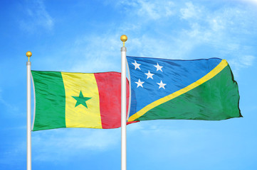 Senegal and Solomon Islands two flags on flagpoles and blue cloudy sky