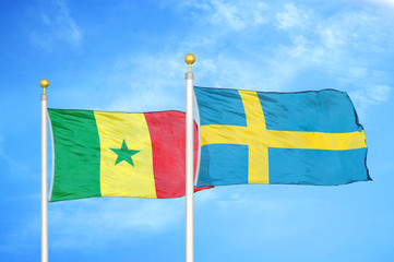 Senegal and Sweden two flags on flagpoles and blue cloudy sky