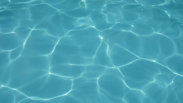 Top view of the blue water texture in the outdoor pool. The surface texture of the ripples clear water in the sunlight