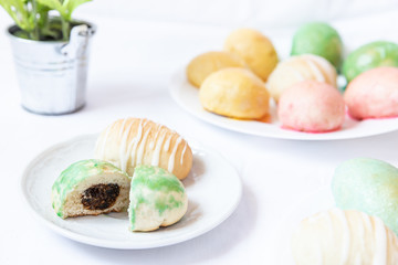 gefüllte bunte und farbige Eier aus Hefe mit Zuckerguss zu Ostern auf Teller auf weißer Decke