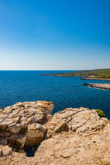 Fototapeta na wymiar The wonderful bay of Porto Selvaggio. In Nardò, Italy, Puglia, Salento. The view of the panorama from the top of the promontory. The blue sea to the horizon. The overhang from the rocky outcrop