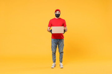 Delivery man employee in red cap blank t-shirt uniform face mask glove hold empty cardboard box isolated on yellow background studio Service quarantine pandemic coronavirus flu virus 2019-ncov concept