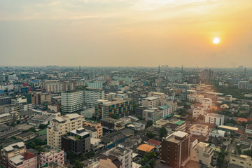 landscape photograph of Asian developing country of Thailand, mass building city scape with construction crane in background and evening sunset setting, above aerial top view looking down on busy city