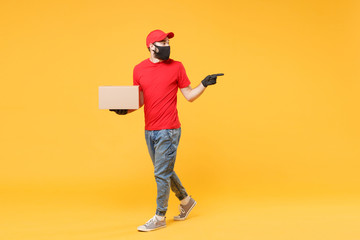 Delivery man employee in red cap blank t-shirt uniform face mask glove hold empty cardboard box isolated on yellow background studio Service quarantine pandemic coronavirus flu virus 2019-ncov concept