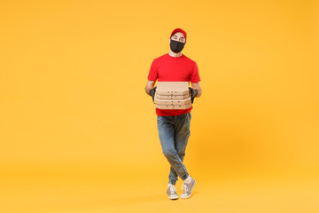 Fototapeta na wymiar Delivery man employee in red cap t-shirt uniform black mask gloves give food order pizza boxes isolated on yellow background studio. Service quarantine pandemic coronavirus virus flu 2019-ncov concept