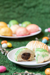 gefüllte bunte und farbige Eier aus Hefe mit Zuckerguss zu Ostern auf Teller und grünem Gras Grund