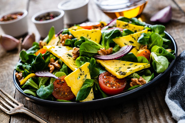 Fresh salad - blue cheese, cherry tomatoes, vegetables and walnuts on wooden background