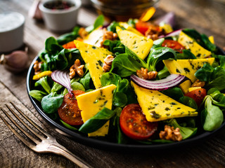 Fresh salad - blue cheese, cherry tomatoes, vegetables and walnuts on wooden background