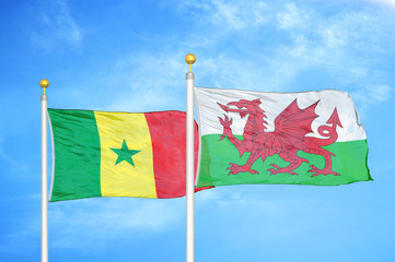 Senegal and Wales two flags on flagpoles and blue cloudy sky