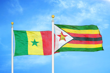 Senegal and Zimbabwe two flags on flagpoles and blue cloudy sky