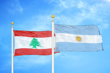 Lebanon and Argentina  two flags on flagpoles and blue cloudy sky