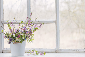 spring flowers in white bucket on old white windowsill