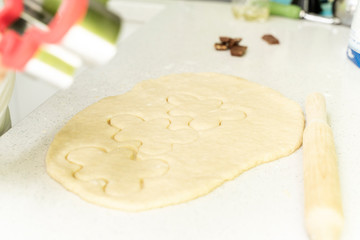 rolled dough with a rolling pin lies on the kitchen worktop, 3 cookies in the shape of little men are carved on the dough.culinary background
