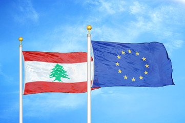Lebanon and European Union two flags on flagpoles and blue cloudy sky