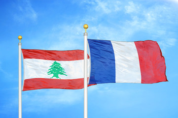 Lebanon and France two flags on flagpoles and blue cloudy sky
