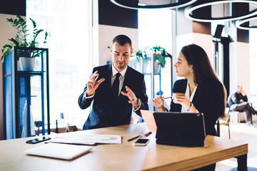 Caucasian male and female colleagues discussing business ideas during collaboration meeting for...
