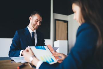 Successful formally dressed partners search solutions during brainstorming meeting in office, Caucasian employees collaborating on management project during working day at table desktop with touch pad