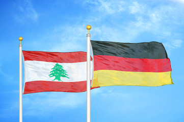 Lebanon and Germany two flags on flagpoles and blue cloudy sky