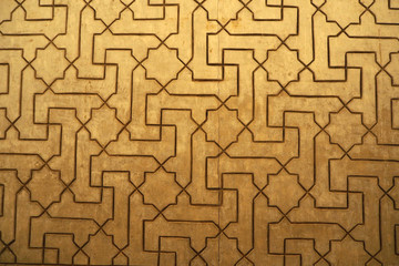 The medieval decorative relief geometric Islamic ornament on the yellow limestone wall in the palace. 