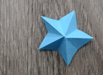 A blue origami star on wooden