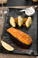 Grilled salmon steak fillets with mashed potato on stone plate on the table at restaurant