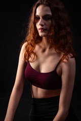 Fototapeta na wymiar Portrait of a young curly girl in a dark studio