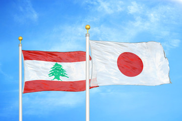 Lebanon and Japan two flags on flagpoles and blue cloudy sky